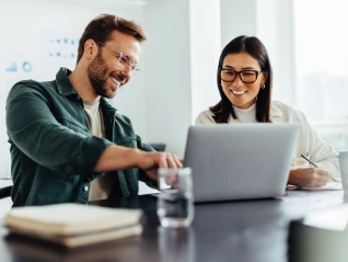 two coworkers discussing something on a laptop